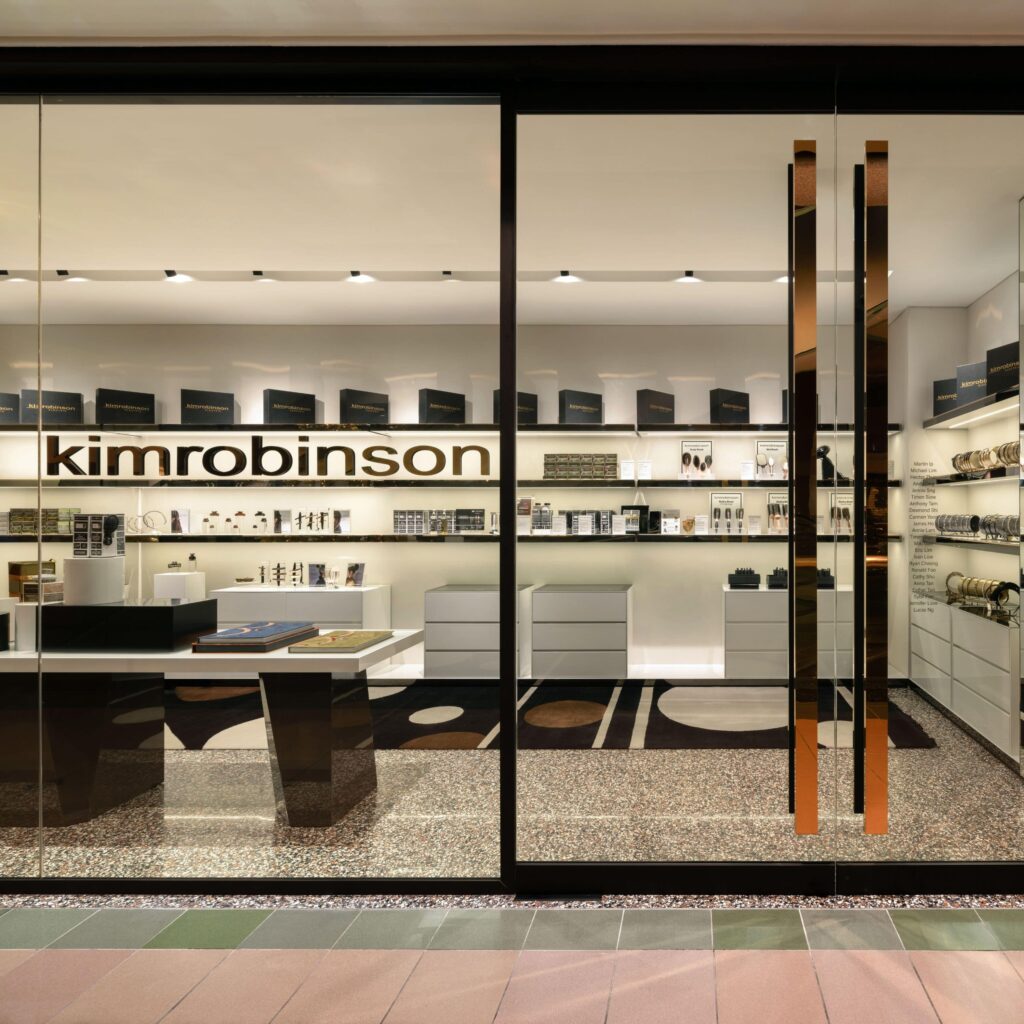 Storefront with a glass facade displays "kimrobinson" sign. Inside, shelves hold various beauty products. A counter and modern decor are visible.